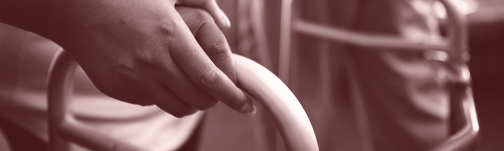 Cropped hands of nurse assisting woman in walking with walker at retirement home