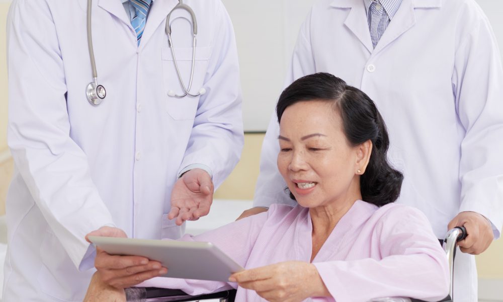 Cheerful aged woman reading doctors presctiption on digital tablet